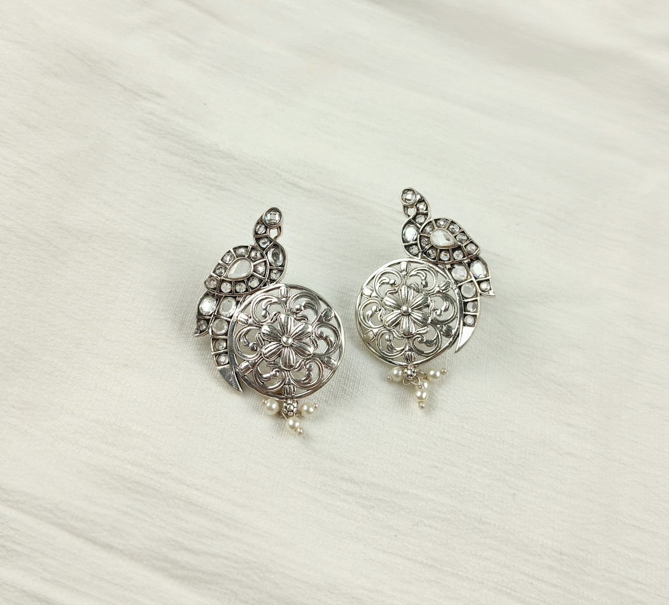 a pair of silver colored earrings on a white background